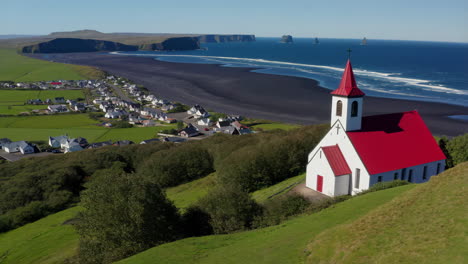 panoramic view of a church and village overlooking a black sand beach and ocean
