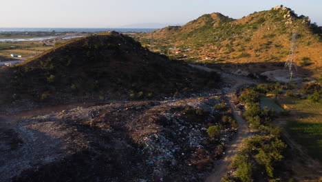 Dumping-ground-near-salt-fields-and-plantation,-birds-flying