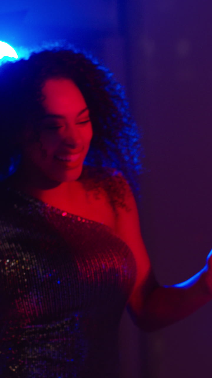 video vertical de dos mujeres bailando en un club nocturno o bar bebiendo alcohol con luces brillantes en el fondo