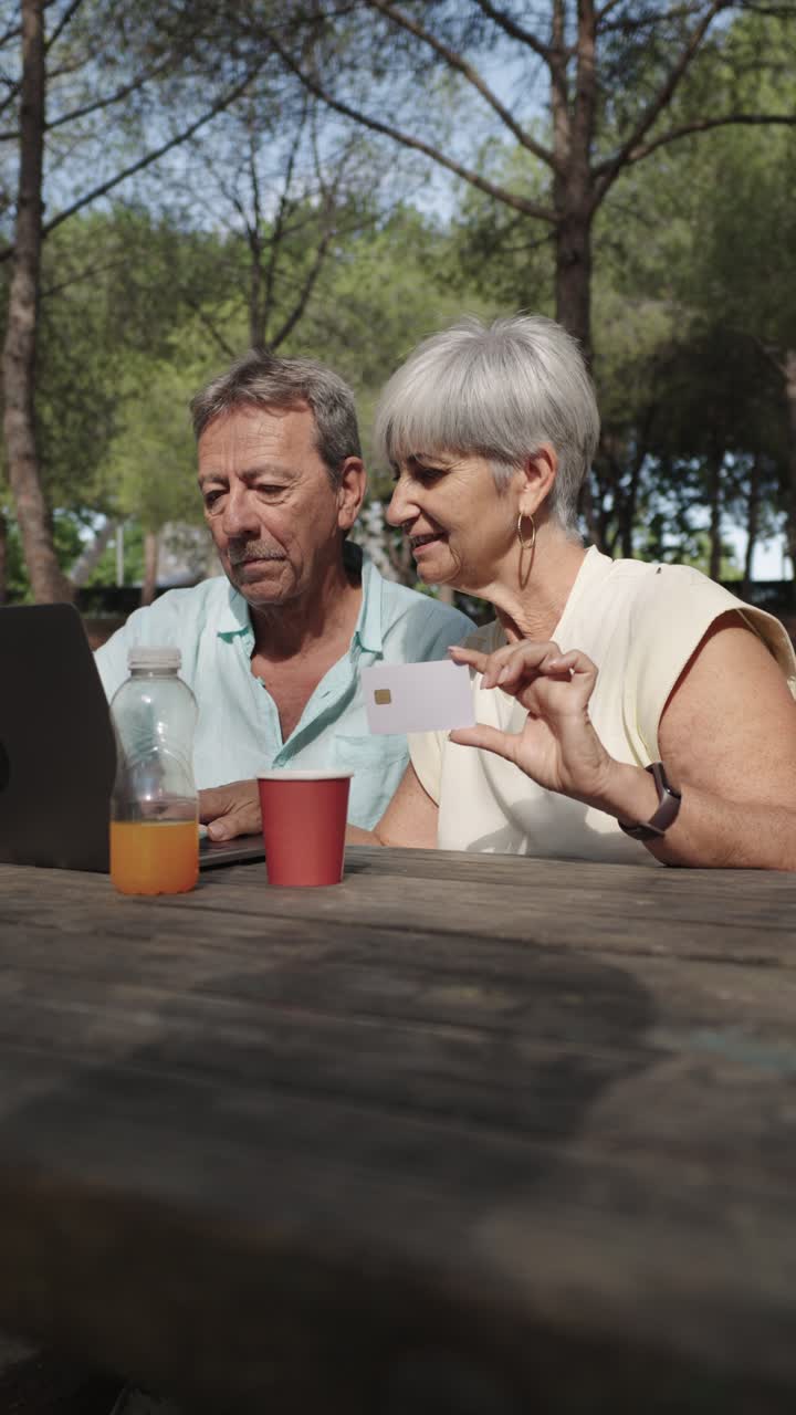 Pareja de ancianos disfrutando de compras online en una mesa de picnic