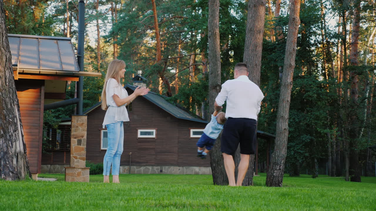 joven familia feliz juega con un niño en el patio trasero de la casa