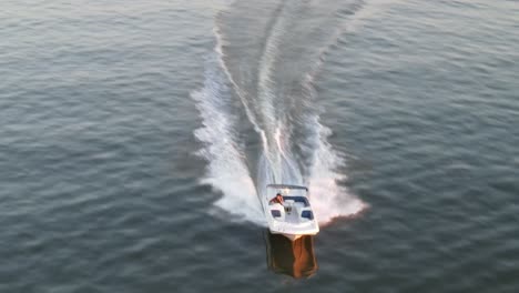 speeding motorboat leaving marks on the water surface during sunset. aerial