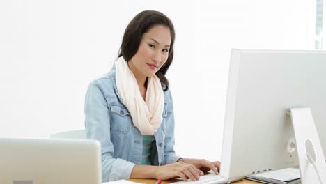 Asian-woman-working-at-desk-using-laptop-and-computer