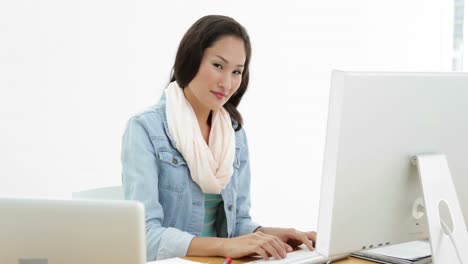 asian woman working at desk using laptop and computer