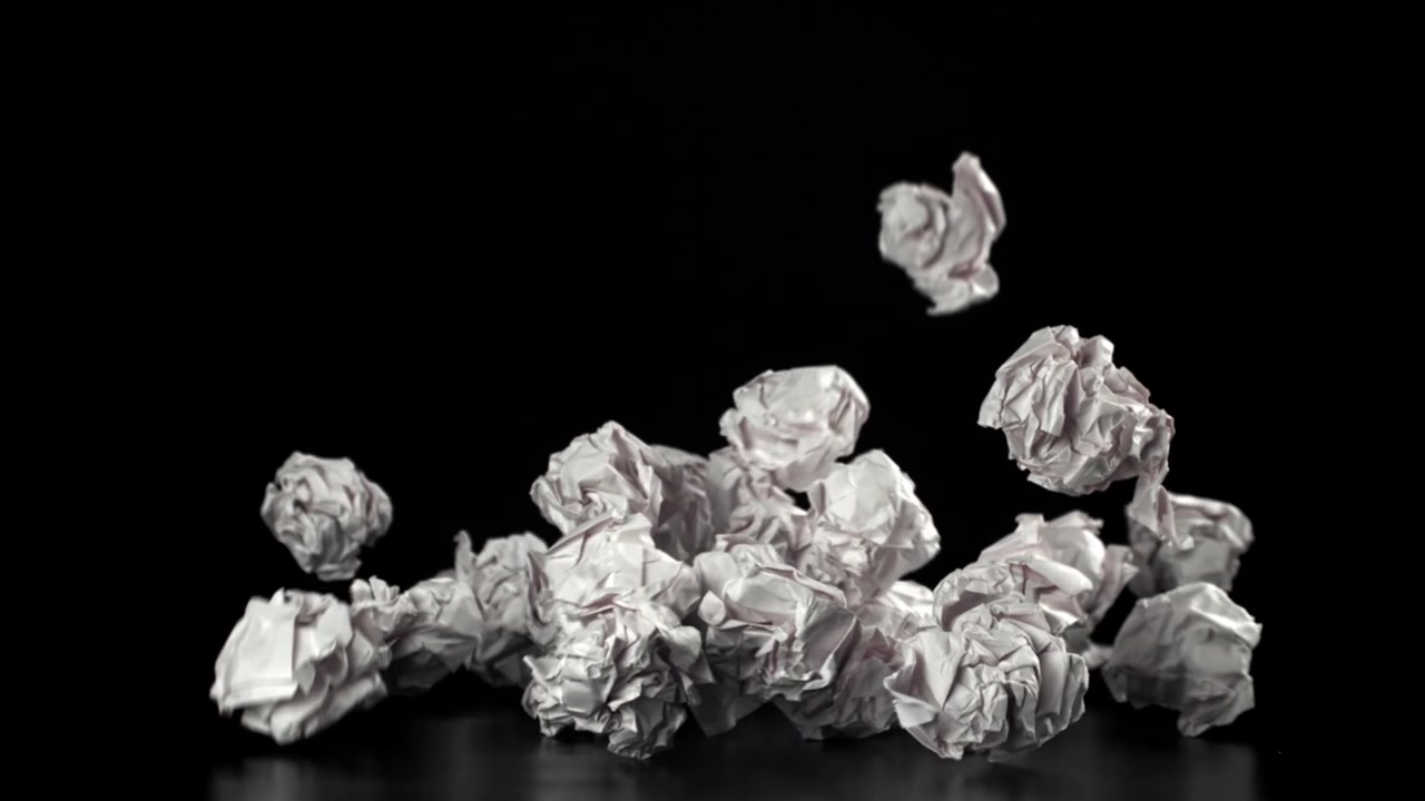 Palline di carta bianca accartocciate che cadono al rallentatore su sfondo nero