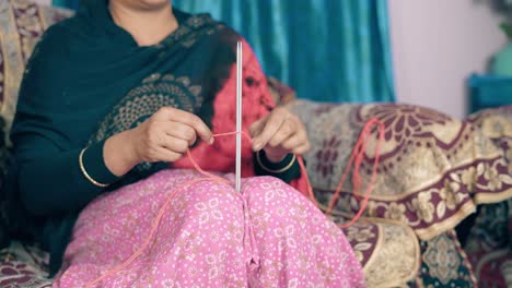 traditional indian woman tart knitting with two needle crafts and red wool