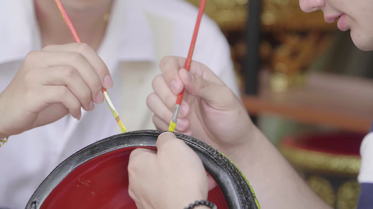 Two people painting a decorative object