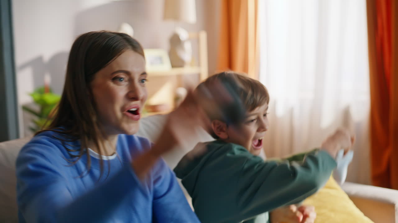 Mother son using consoles playing video game in home living room closeup