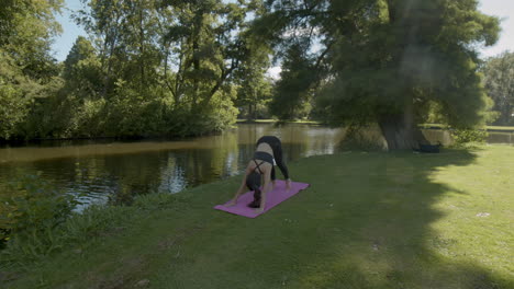 young woman ending yoga exercises in beautiful park