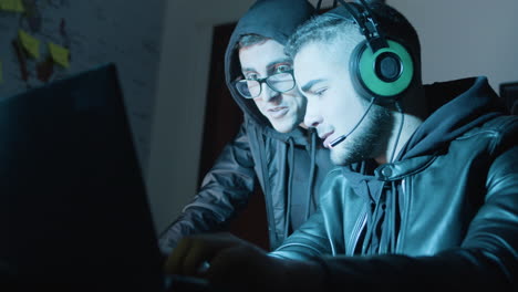 two young hackers working in dark room at night