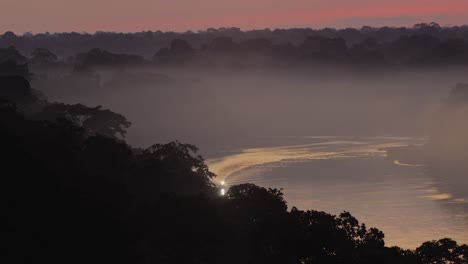 Boat-with-spotlight-cruises-along-Tambopata-River-at-sunset