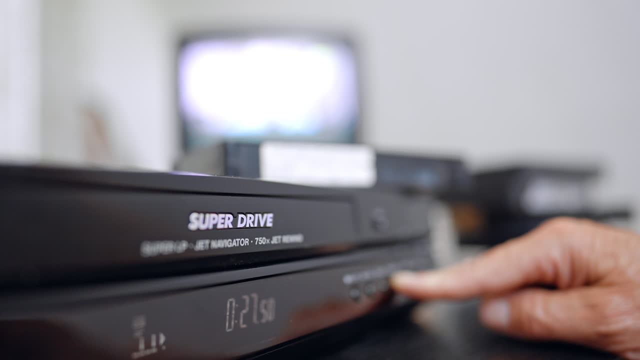 Caucasian male hand presses the button on the panel of VHS player. Close up. Glimmering screen at blurred backdrop