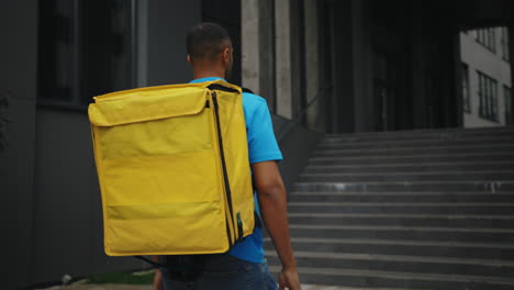 delivery person carrying a yellow backpack