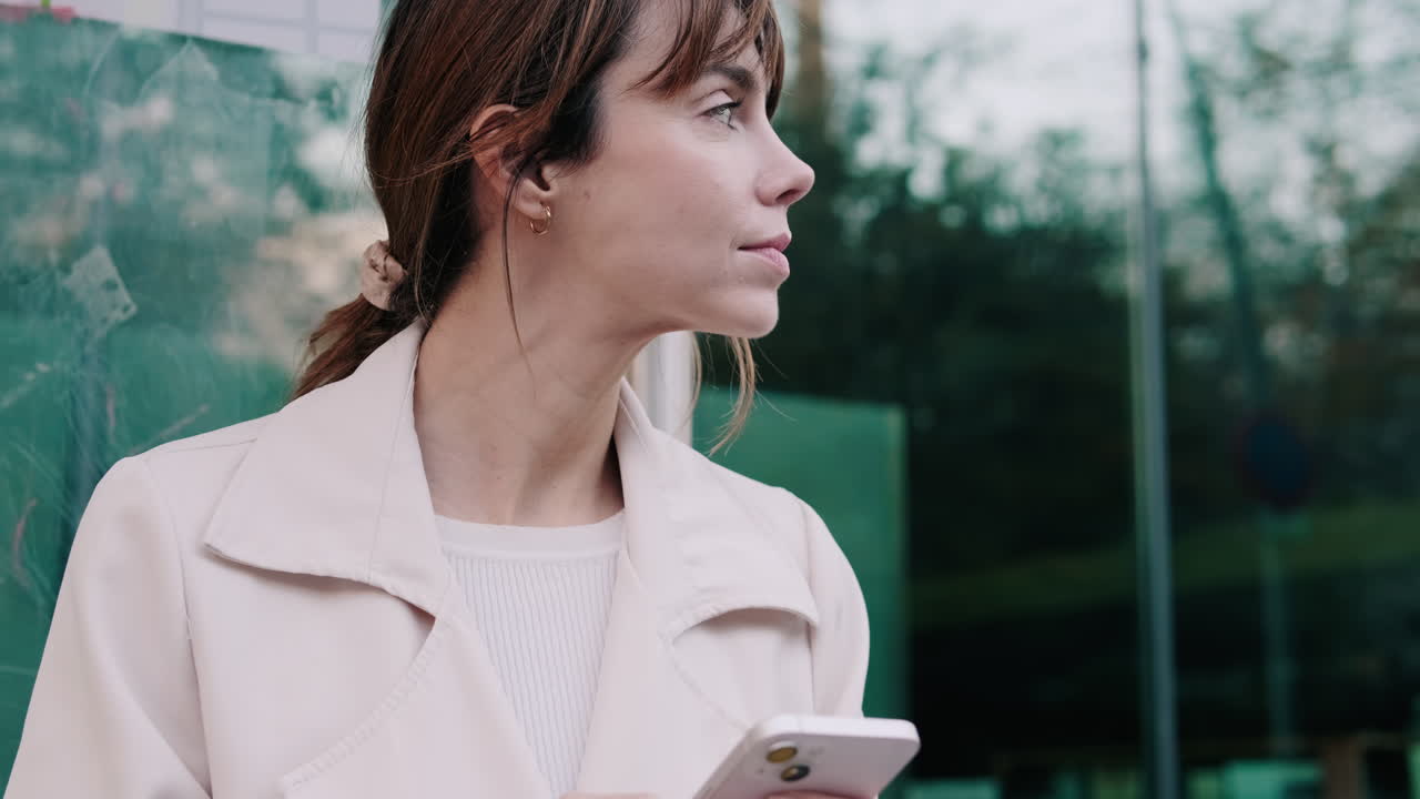 Giovane donna che usa lo smartphone mentre aspetta all'aperto