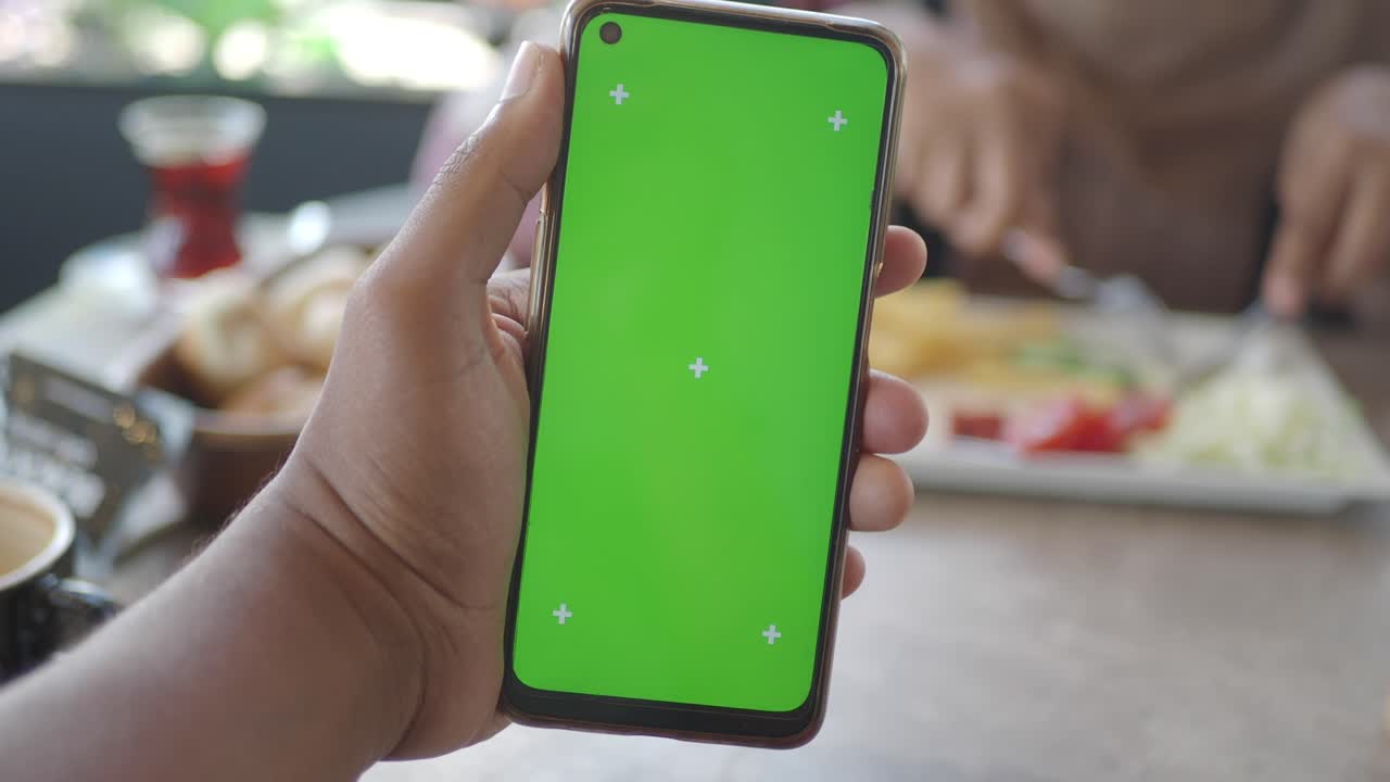 Smartphone with Green Screen Held in Hand