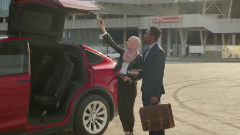 business people discussing near electric car