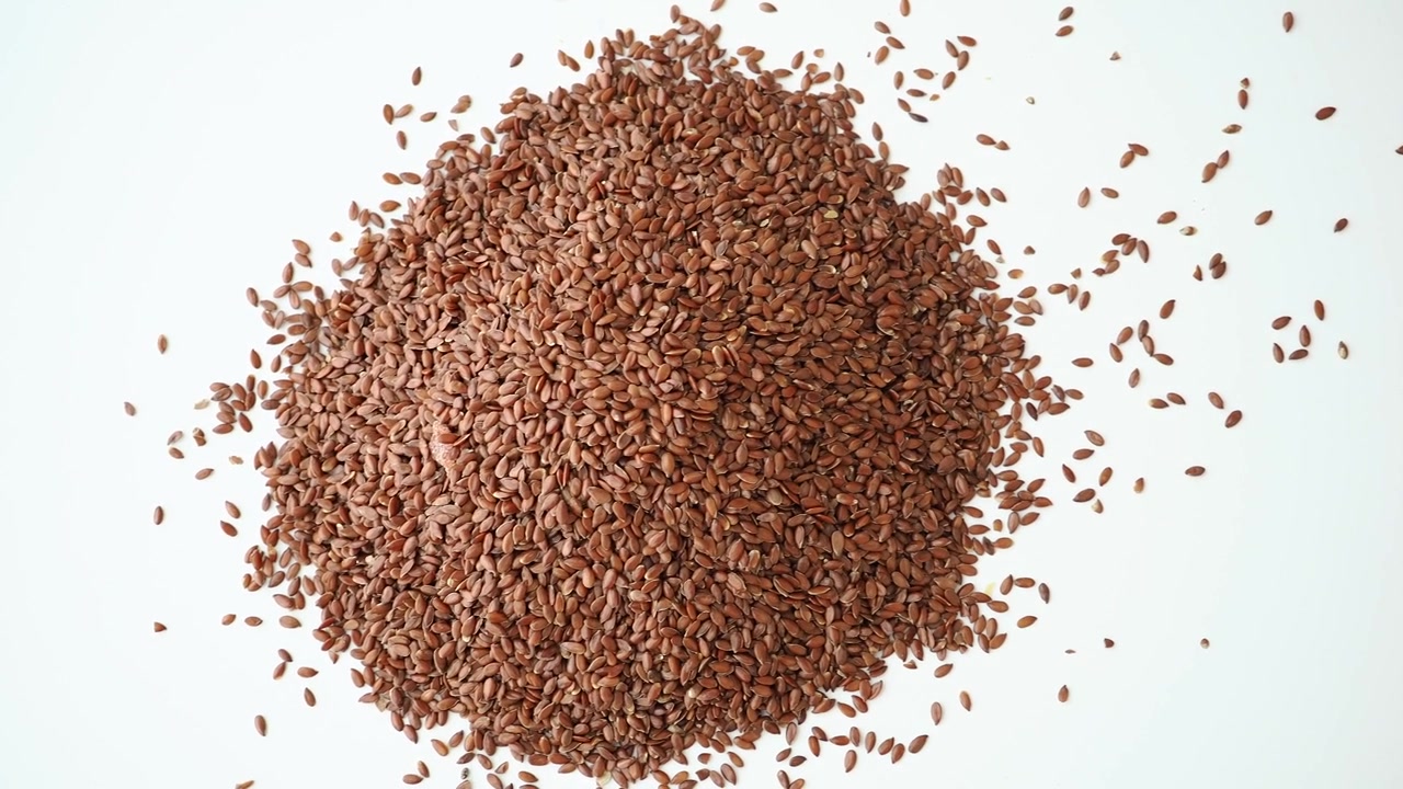 Mucchio di semi di lino marroni su sfondo bianco