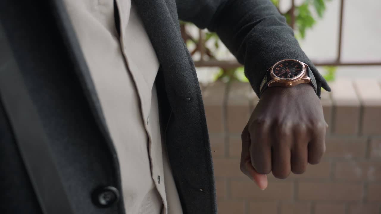 Un hombre se detiene en el pasillo, comprueba su reloj de pulsera durante cinco segundos, junta las palmas de las manos y luego las relaja, respira hondo antes de dar una zancada, concentración puntual, la tensión aumenta hacia el movimiento, la conciencia del tiempo impulsa el siguiente paso.