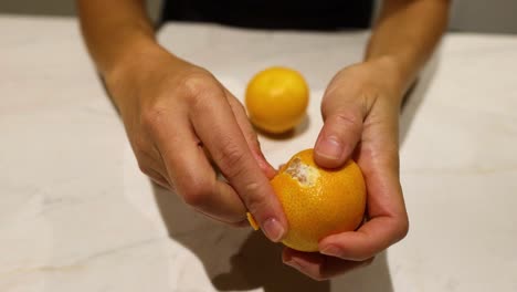 hands peeling an orange on a countertop