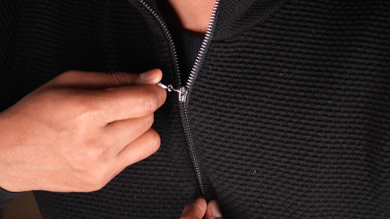 Close-up of a Person Zipping Up a Black Jacket