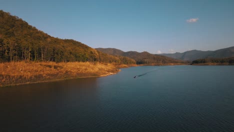 傳統泰國船隻在藍色水域航行, 背景是斯里蘭納國家公園的mei ngat somboon chon的日落森林.