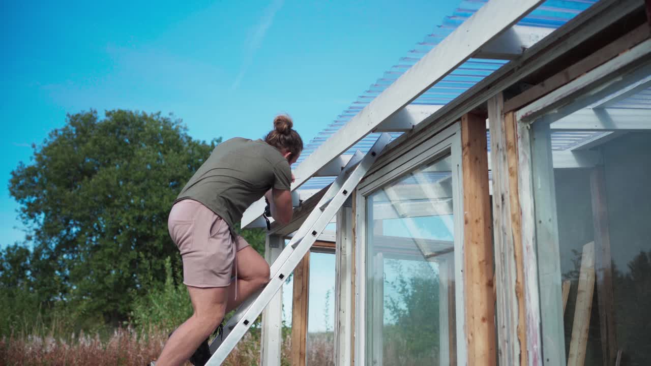 노르웨이 의 인드레 포센 에서 온실 을 짓는 사다리 위 에 있는 사람 - 근접