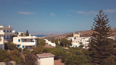 aerial drone shot pulling back from the village of lefkes greece revealing some trees in the foreground