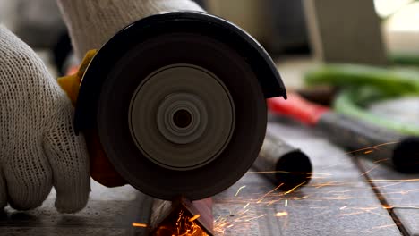 hands of mechanic using electric grinder to cutting the steel with fire light flicker