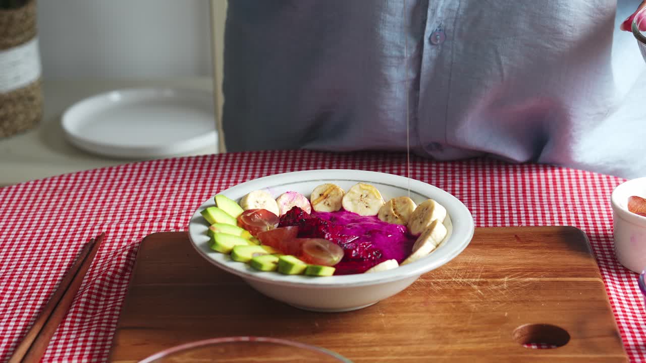 manos de la mujer preparando comida saludable con la adición de miel en la mezcla de frutas en el cuenco
