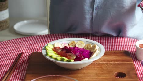 woman hands preparing healthy food with adding honey into mix fruit in bowl