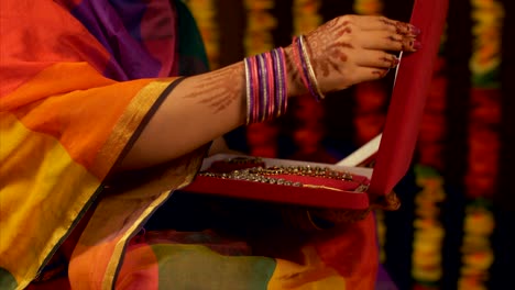 an indian housewife in traditional dress and mehndi checking out her kundan jewellery set