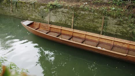 Medium-wide-shot-of-a-small-wooden-boat-floating-on-a-calm-river