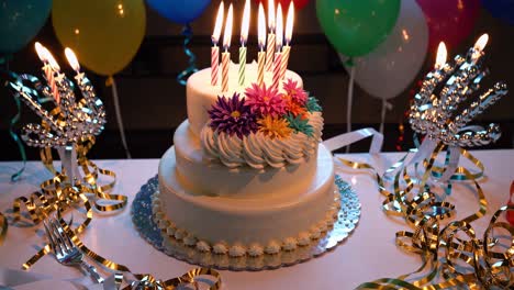 a festive birthday cake with lit candles, shot from a slightly elevated angle