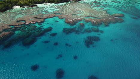 inclinación lenta por encima del agua cristalina que revela la costa de maré, nueva caledonia - antena