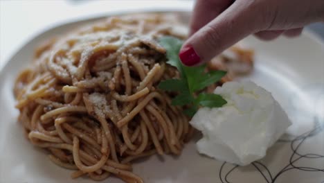 decorating a pasta portion with an arugula leaf