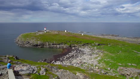 Flug-über-Die-Meereslandschaft-In-Richtung-Eines-Leuchtturms,-Während-Ein-Tourist-Die-Aussicht-Auf-Einer-Steinbank-Genießt