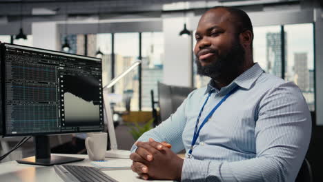 smiling portfolio manager at computer desk evaluates assets based on statistics
