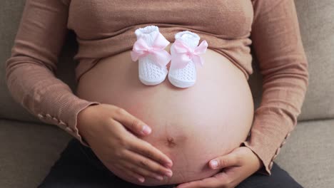 a pregnant woman holding baby shoes