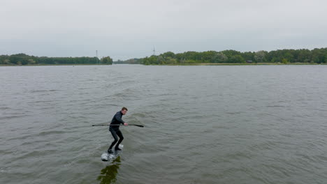 athlete on hydro sup foil surf in wave on a river filmed with drone in front of close up