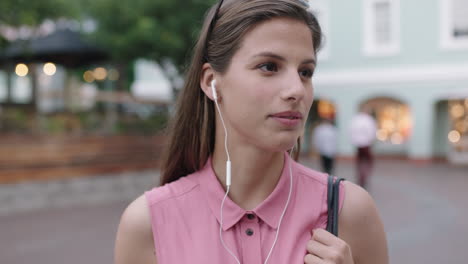 slow motion portrait of young beautiful woman wearing earphones listening to music checking wrist watch smiling cheerful at camera evening urban background