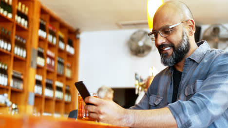 happy man using mobile phone while having beer at counter 4k