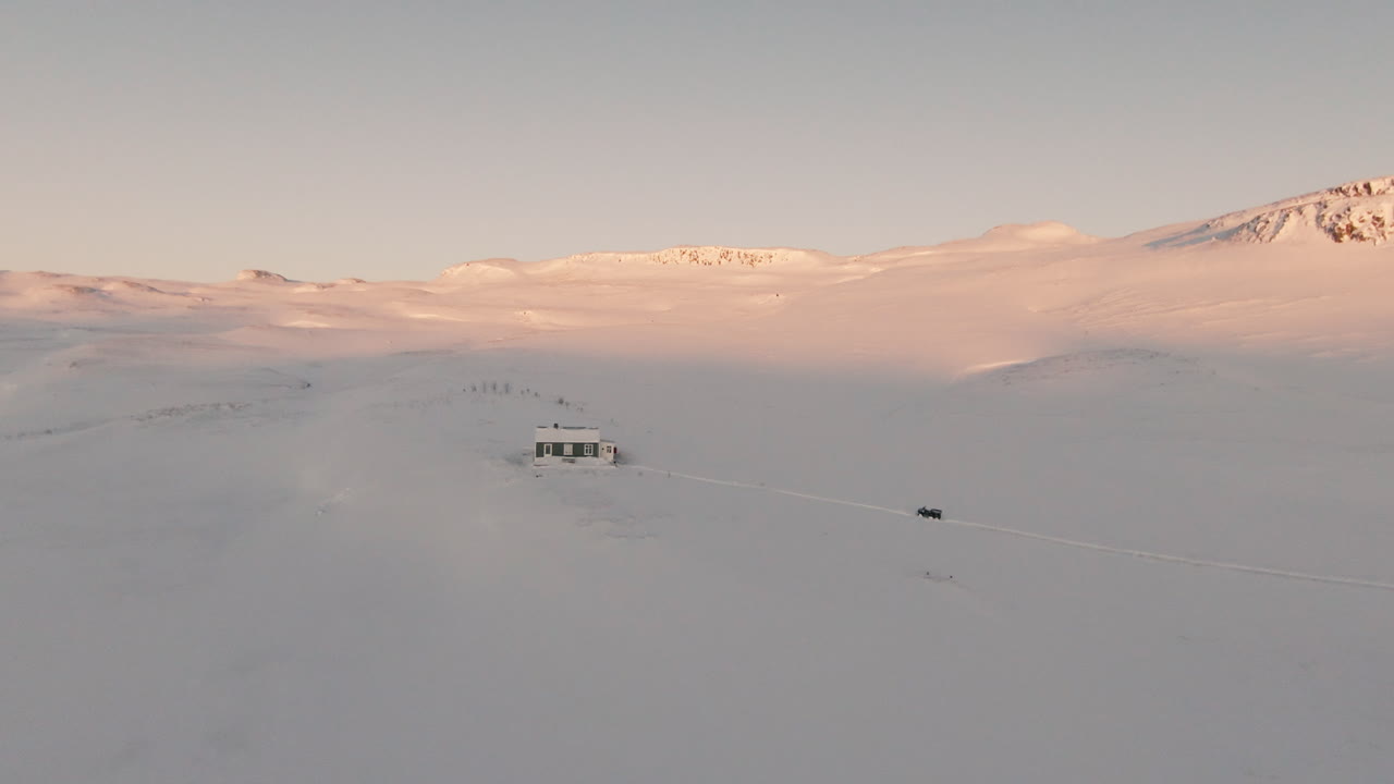 Cabin in snowy mountainscape during sunset, dolly forward