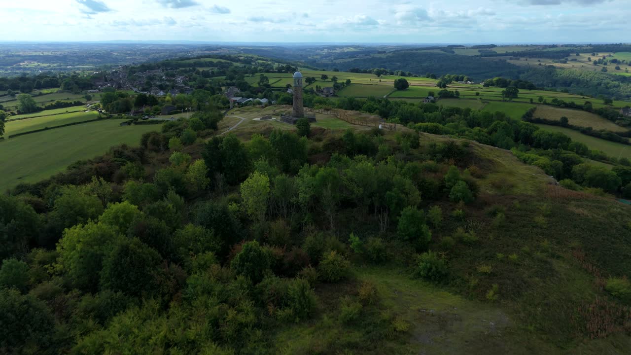 Aerial drone shot of Crick war memorial tower on hilltop surrounded by rolling green hills and valleys, Derbyshire Dales, United Kingdom