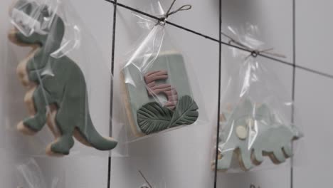 galletas de cumpleaños hechas a mano personalizadas colgadas en un estante en una pastelería haciendo regalos decorados individualmente, cámara lenta de 4k