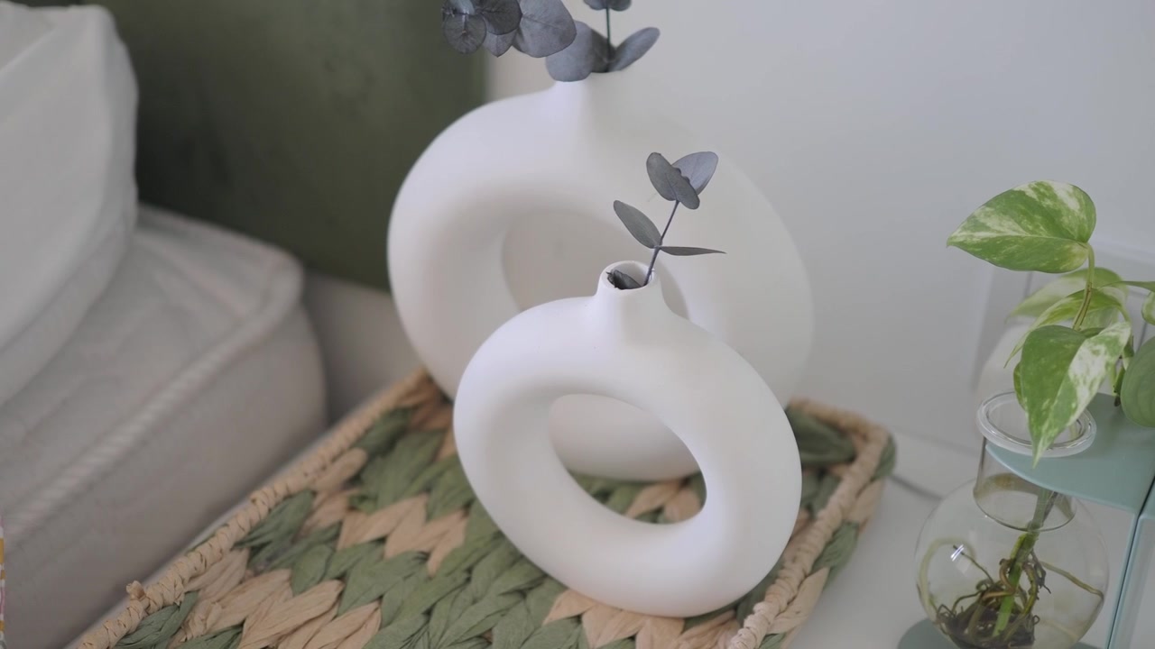 Vases en céramique blancs modernes et minimalistes avec de l'eucalyptus sur un plateau tressé