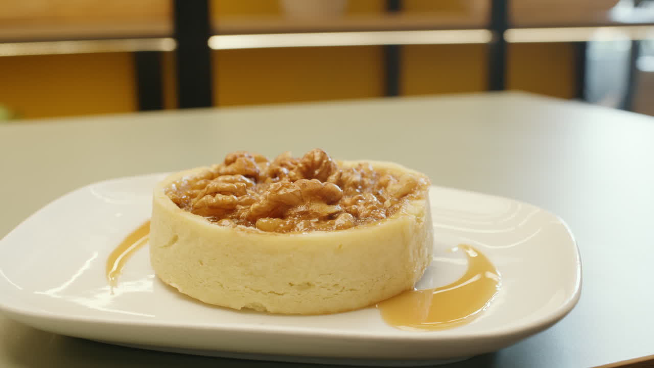 Panning shot of a cheesecake garnished with whole walnuts on top, highlighting its creamy texture and crunch