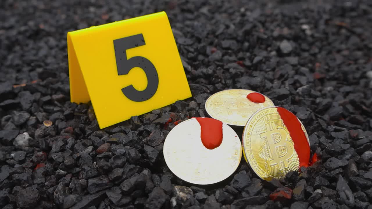 Close up video of golden shiny and reflective bitcoin cryptocurrency or crypto money coins covered in bloodstains that are next to a yellow police crime scene forensic investigation marker on gravel