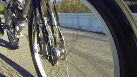 close up of the wheels of a motorized bicycle through the countryside on a two lane road
