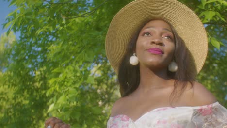 Mujer-Negra-Mirando-A-Su-Alrededor-Y-Sonriendo-En-Un-Picnic-En-El-Parque-De-ángulo-Bajo