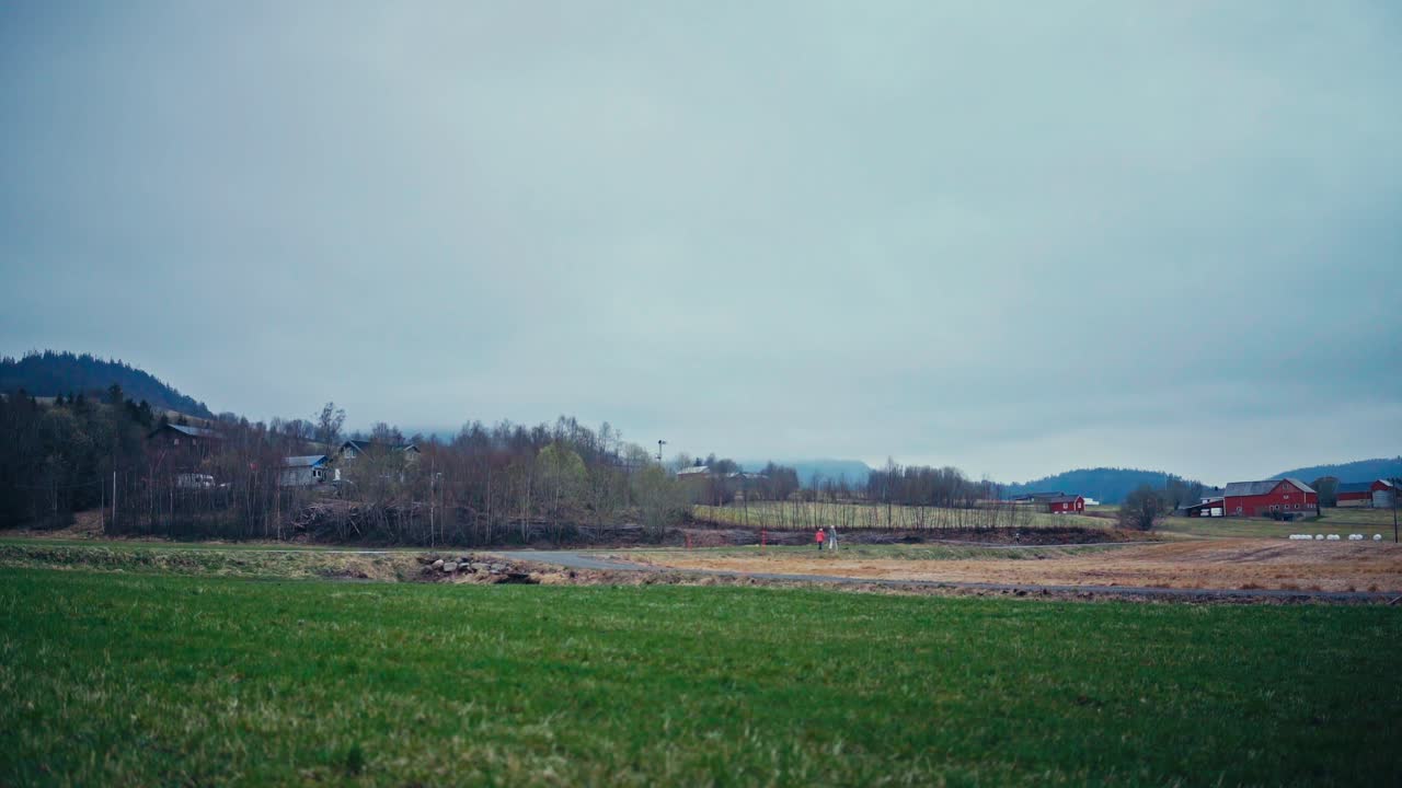 Car Passes On The Road Overlooking A Rural Village In Norway. Timelapse